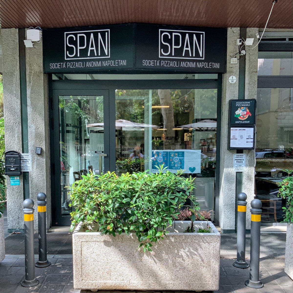 La facciata di SPAN in via Laura Bassi, con l'insegna nera e il dehors